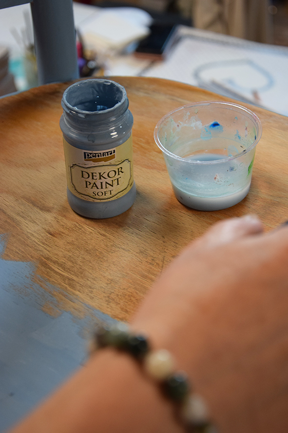 Žena natiera stoličkou modrou Decor paint farbou s pomocou &scaron;tetca.